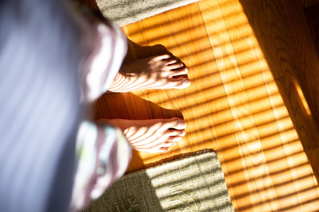 a person standing on a wooden floor with their bare feet